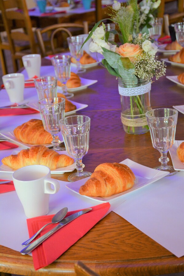 A dining table set with croissants, wine glasses, and a vase with flowers. - Les Lavandières de Fontaine (Fontaine-lès-Vervins)