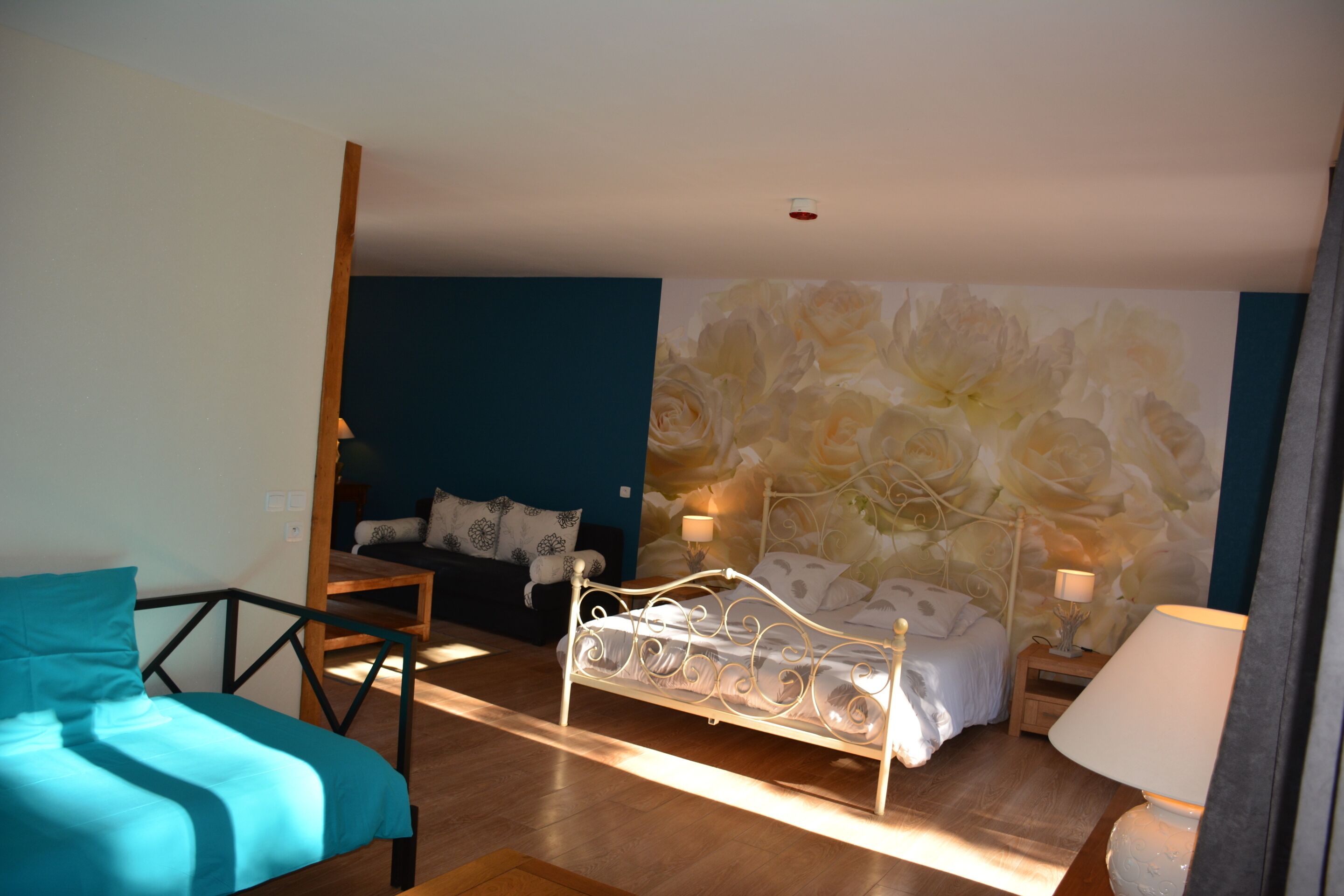 Een slaapkamer met een bed, een stoel, een nachtkastje en een wand met een bloemmotief.