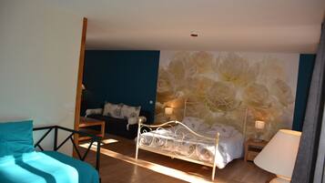 Een slaapkamer met een bed, een stoel, een nachtkastje en een wand met een bloemmotief.