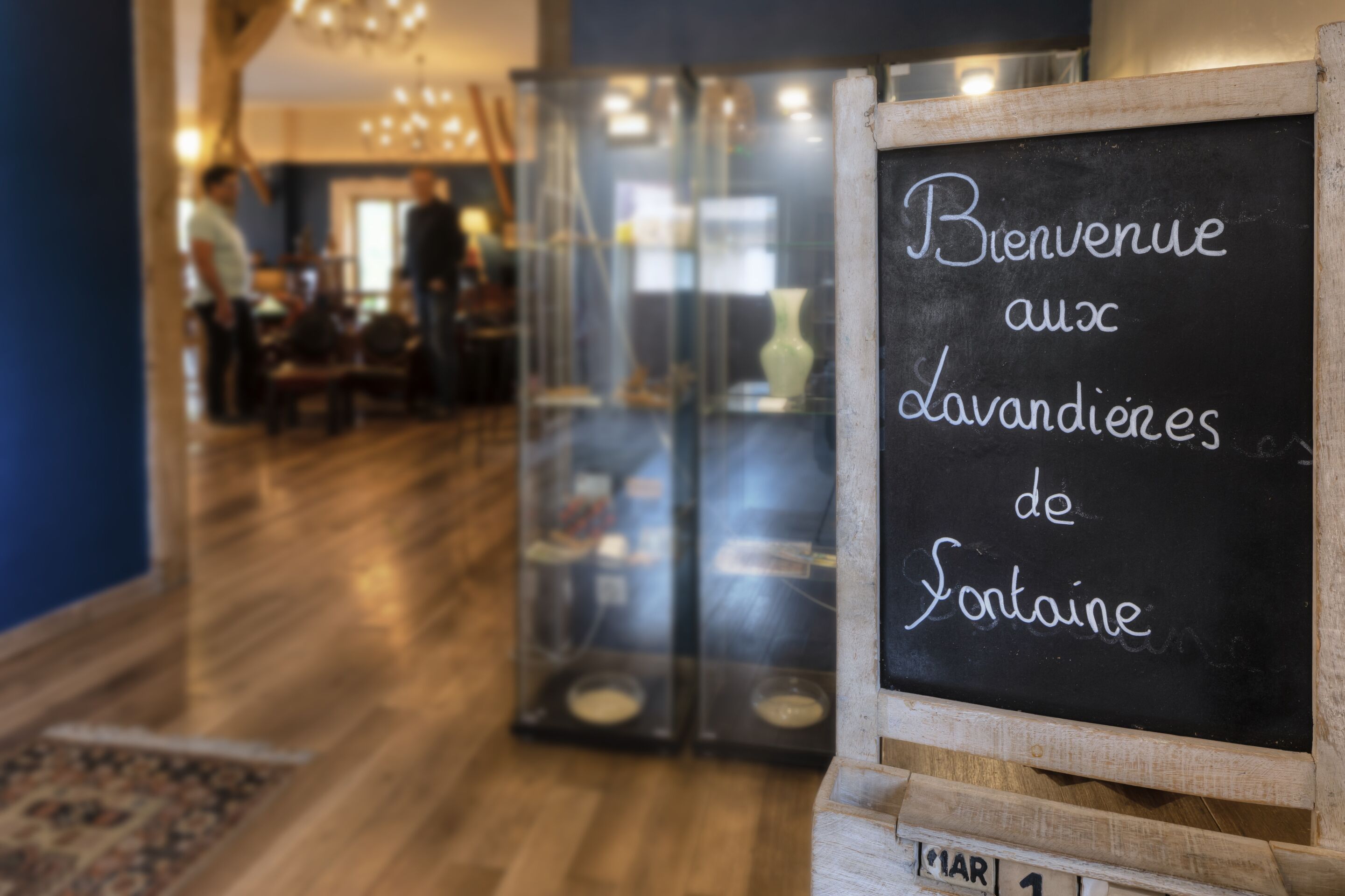 A blackboard with 'Bienvenue aux lavandieres de Fontaine' written on it, indicating a welcome to the bathroom facilities of Fontaine.
