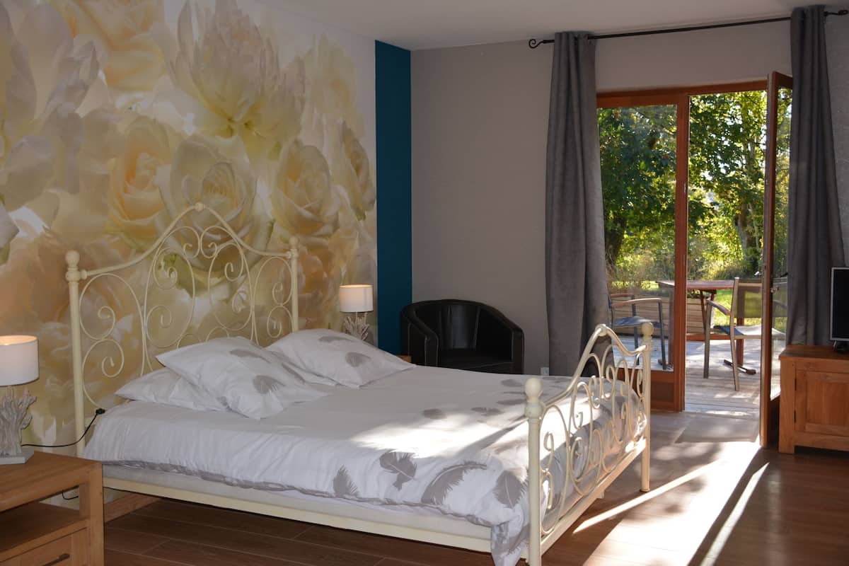 Une chambre à coucher avec un lit, une table de chevet, une lampe, une chaise et un téléviseur.