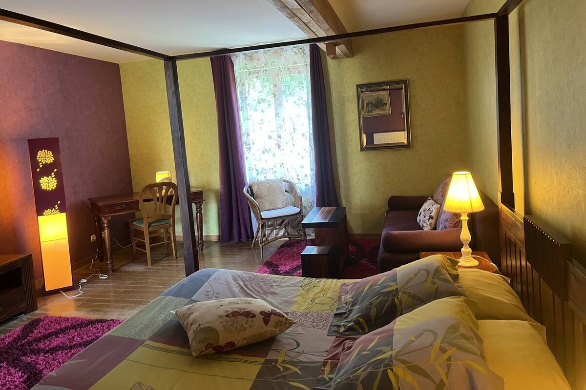 Une chambre d’hôtel avec un lit, une chaise, une petite table et une lampe.
