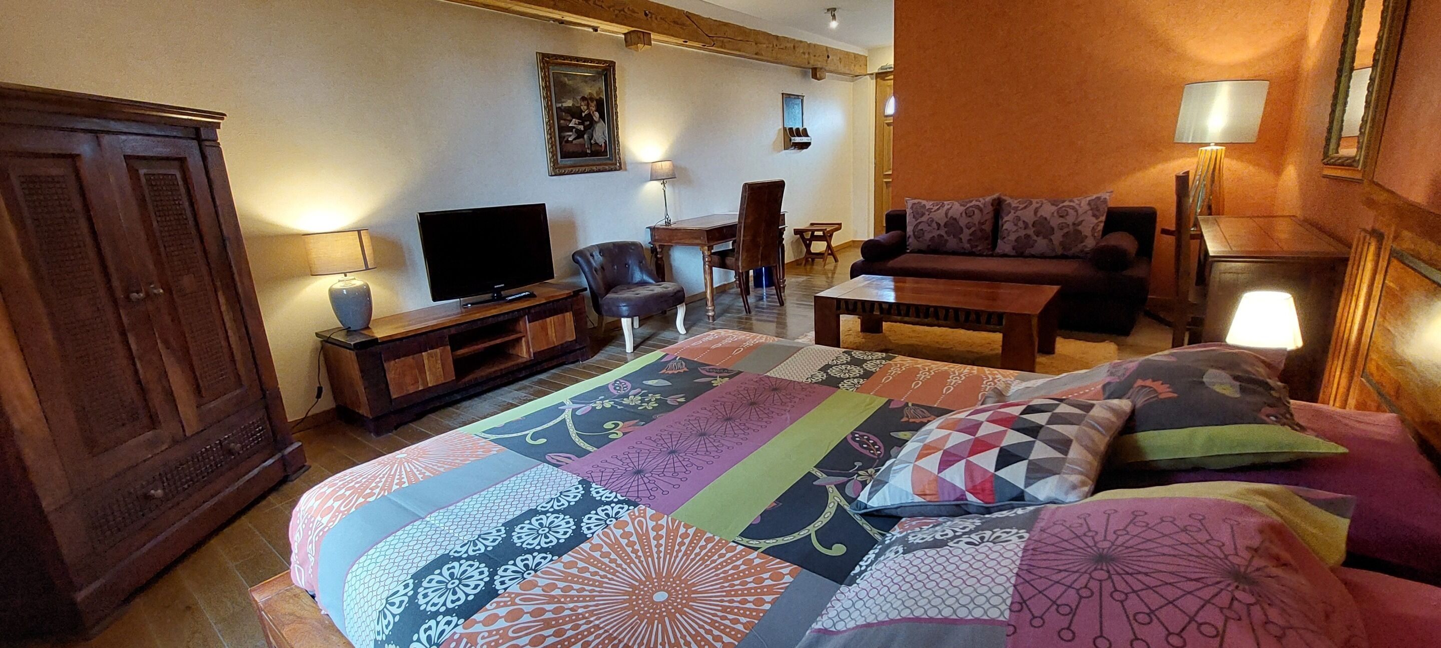 Una habitación de hotel con una cama grande, televisión, escritorio y sofá.