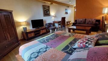 Una habitación de hotel con una cama grande, televisión, escritorio y sofá.