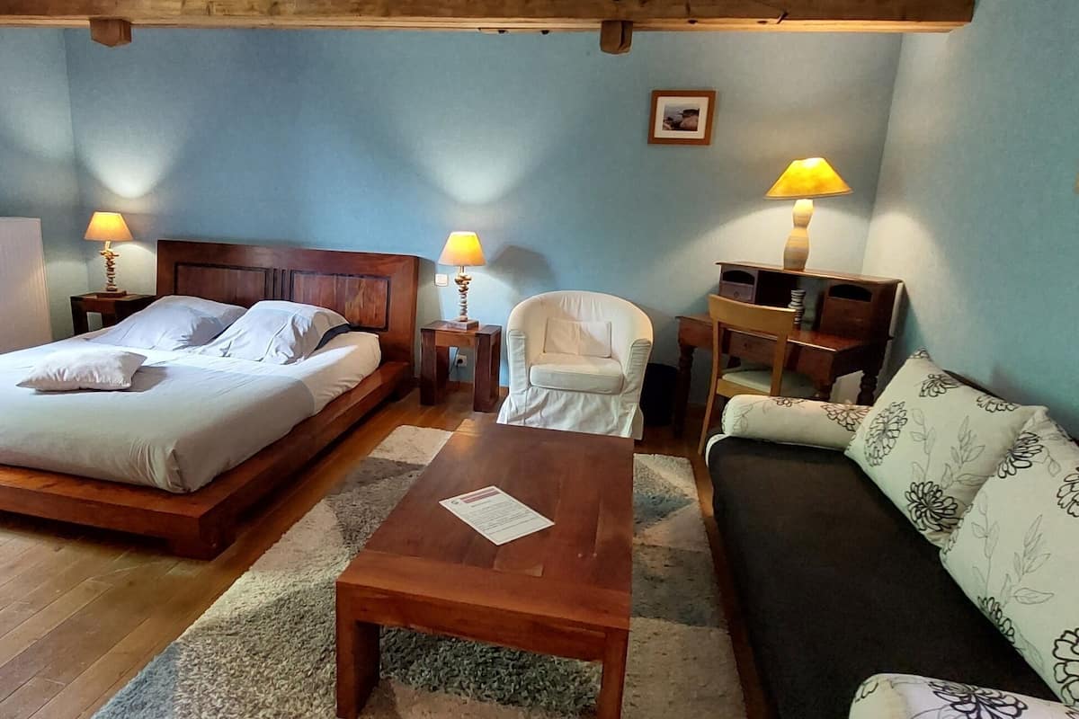 Une chambre à coucher comprenant un lit, deux tables de chevet avec des lampes, une chaise, un canapé et une petite table.