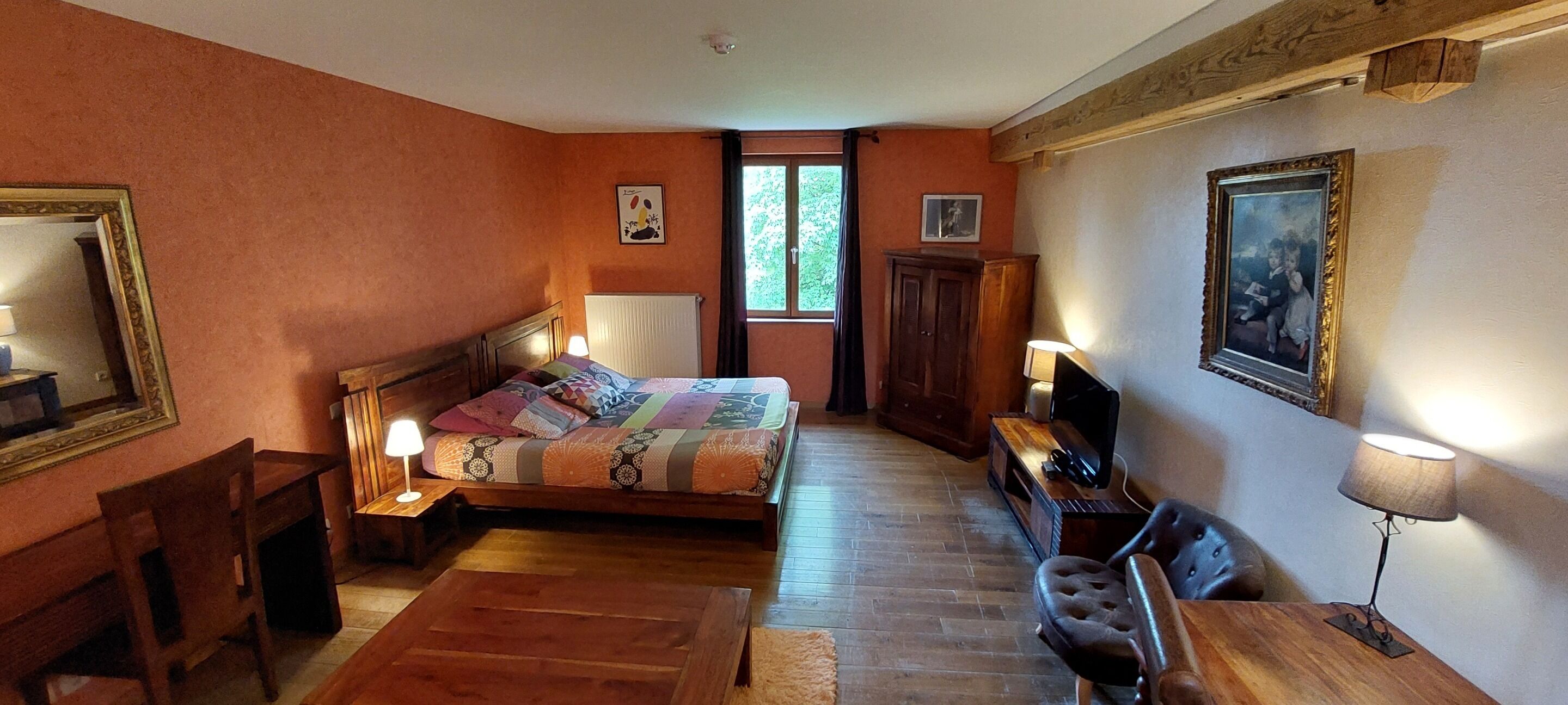 Un dormitorio acogedor con cama de madera, escritorio, silla y televisor.