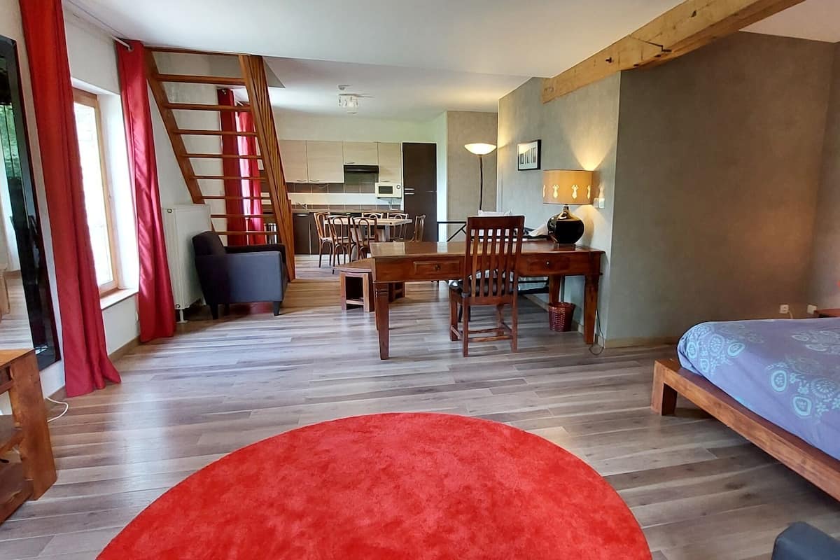 Une chambre à coucher avec un lit, un tapis rouge, un bureau en bois et une chaise.