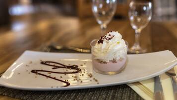 A dessert on a white plate with chocolate sauce and nuts, accompanied by a fork and knife on a placemat.