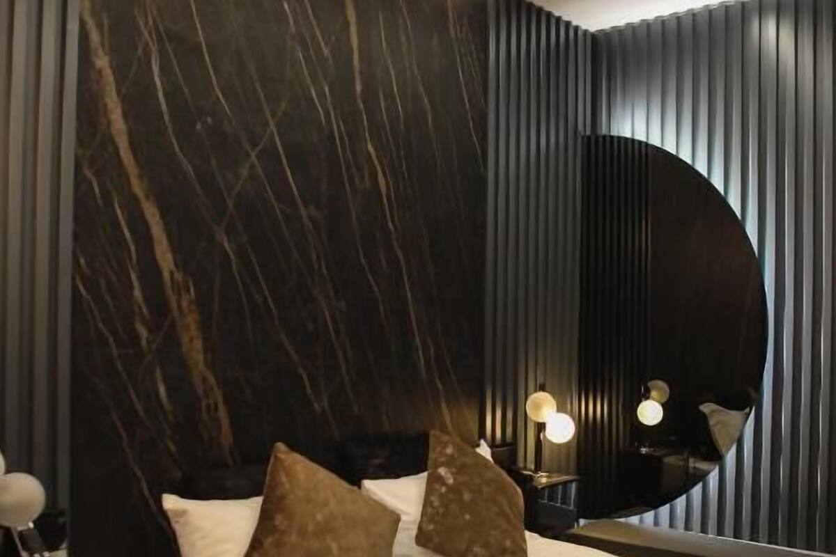 A modern bedroom with a bed, nightstands, and a large mirror.