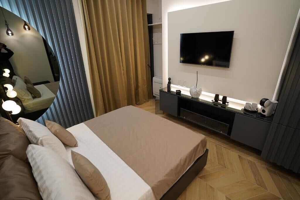 Ein modernes Schlafzimmer mit Bett, Nachttisch, Fernseher und Kleiderschrank.