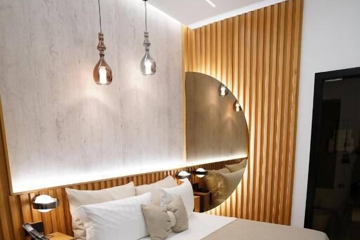 A modern bedroom with a bed, bedside tables, and a large mirror.