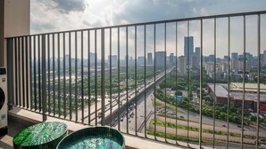 Un balcon offrant une vue sur le paysage urbain, avec notamment un pont et des immeubles de grande hauteur.