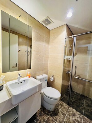 Une salle de bain moderne avec un grand miroir, un lavabo, des toilettes et une douche à parois de verre.
