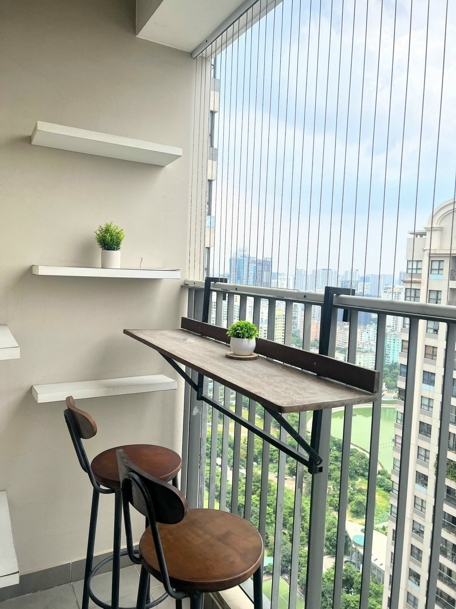 Ein Balkon mit einem Holztisch, zwei Stühlen und einem Blumentopf.