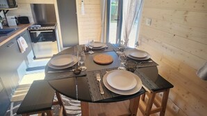 Mesa de comedor preparada para cuatro personas, con platos, cubiertos y vasos. Se ven un microondas y un horno al fondo.