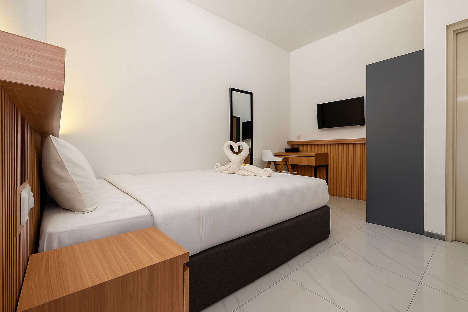A modern hotel room with a large bed, a desk, a flat-screen TV, and a mirror.