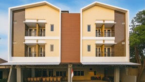A modern two-story building with balconies, a covered outdoor seating area, and a flagpole. - Lume Stay by Sinergi (Semarang)