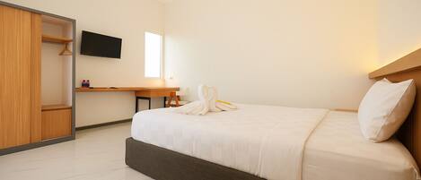 A hotel room with a bed, a desk, a TV, and a wardrobe.