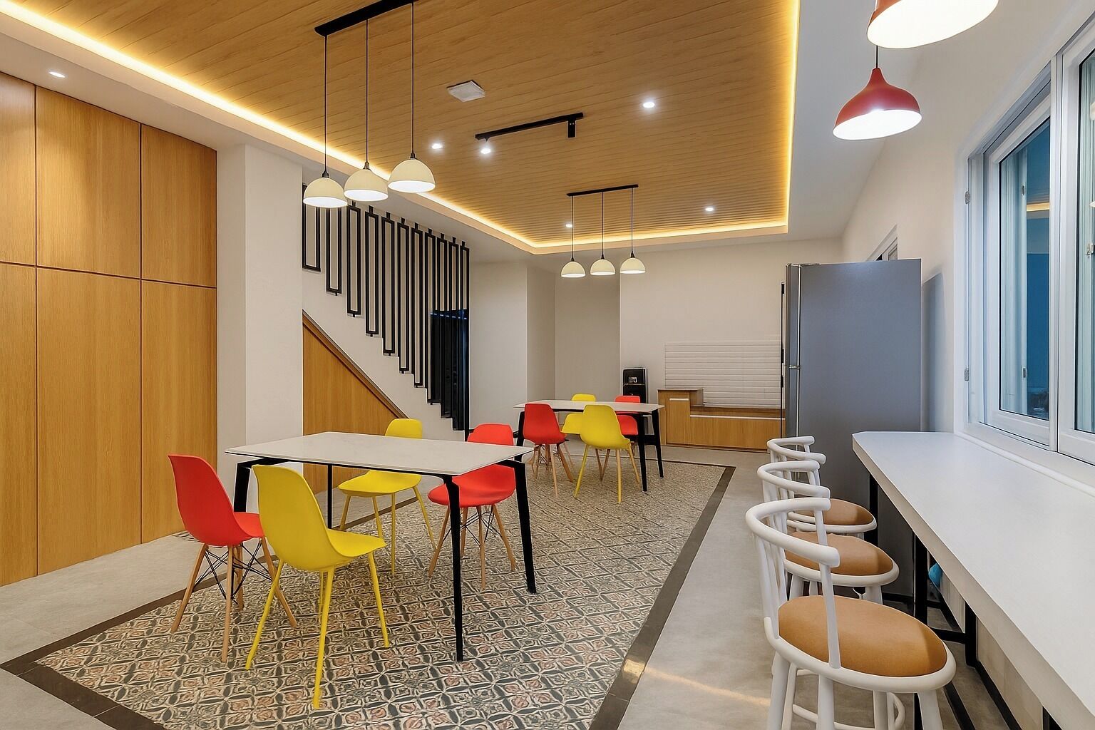 Una cocina moderna con comedor, que incluye una escalera, sillas coloridas e iluminación colgante.