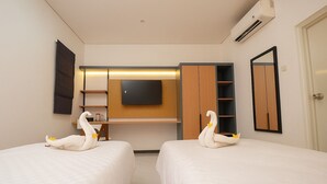 A hotel room with two beds, a TV mounted on the wall, and a wardrobe. - Lume Stay by Sinergi (Semarang)