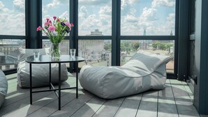 A modern balcony with a round table, two white cushioned chairs, and a vase of flowers. - Długa 17 Residence (Kraków)
