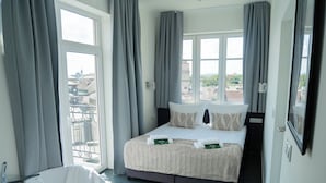 A hotel room with a bed, a bathtub, and a view of the city. - Długa 17 Residence (Kraków)