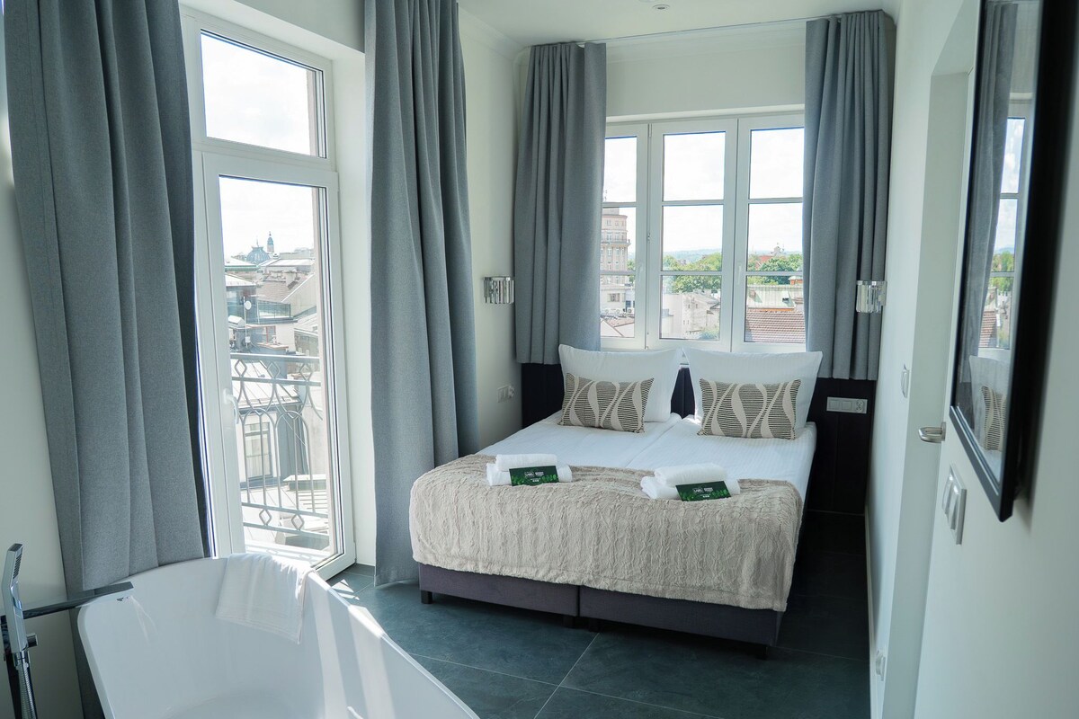 Una habitación de hotel con una cama, una bañera y vistas a la ciudad.