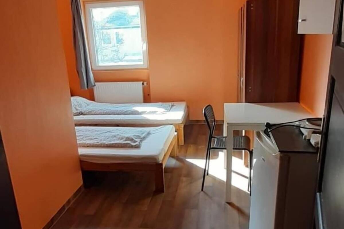 Une petite chambre comprenant un lit, une petite table et un réfrigérateur.
