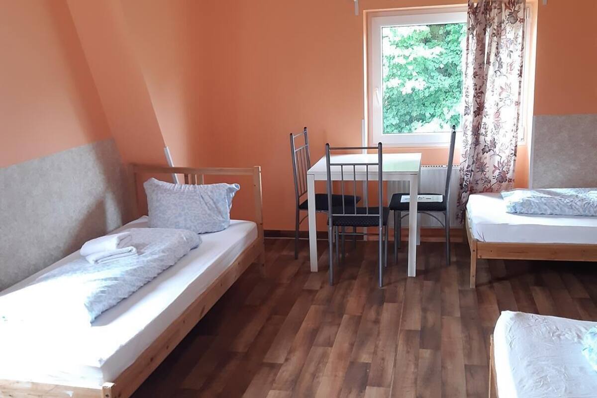 Une chambre avec deux lits simples, une table avec des chaises et une fenêtre avec des rideaux.