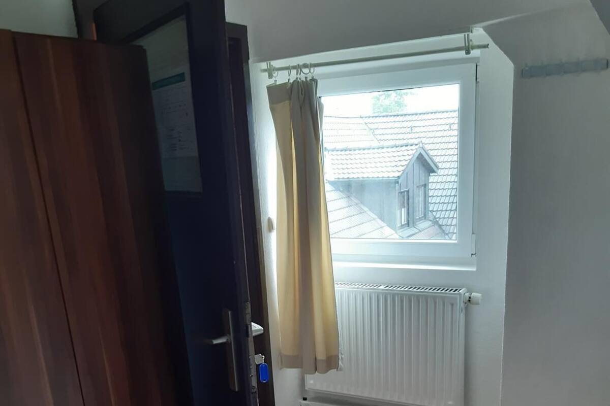 Une pièce avec une armoire en bois, un radiateur et une fenêtre avec des rideaux.