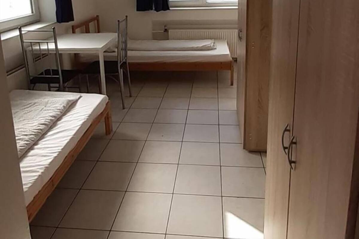 Une chambre de dortoir équipée d’un lit superposé, d’un bureau, d’une chaise, d’un radiateur et d’une armoire.