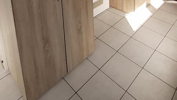 A room with two wooden wardrobes and tiled flooring.