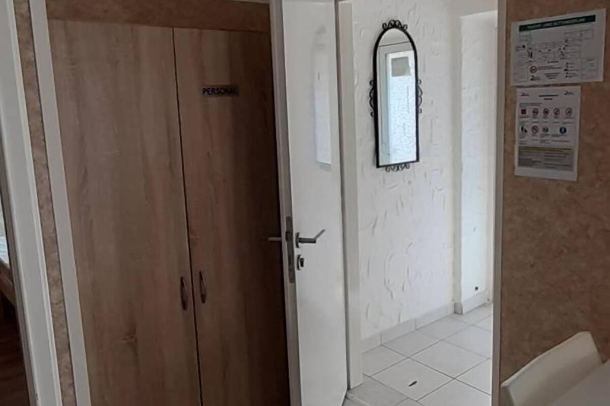 Une pièce avec une armoire en bois, une porte blanche, un miroir et un sol carrelé.