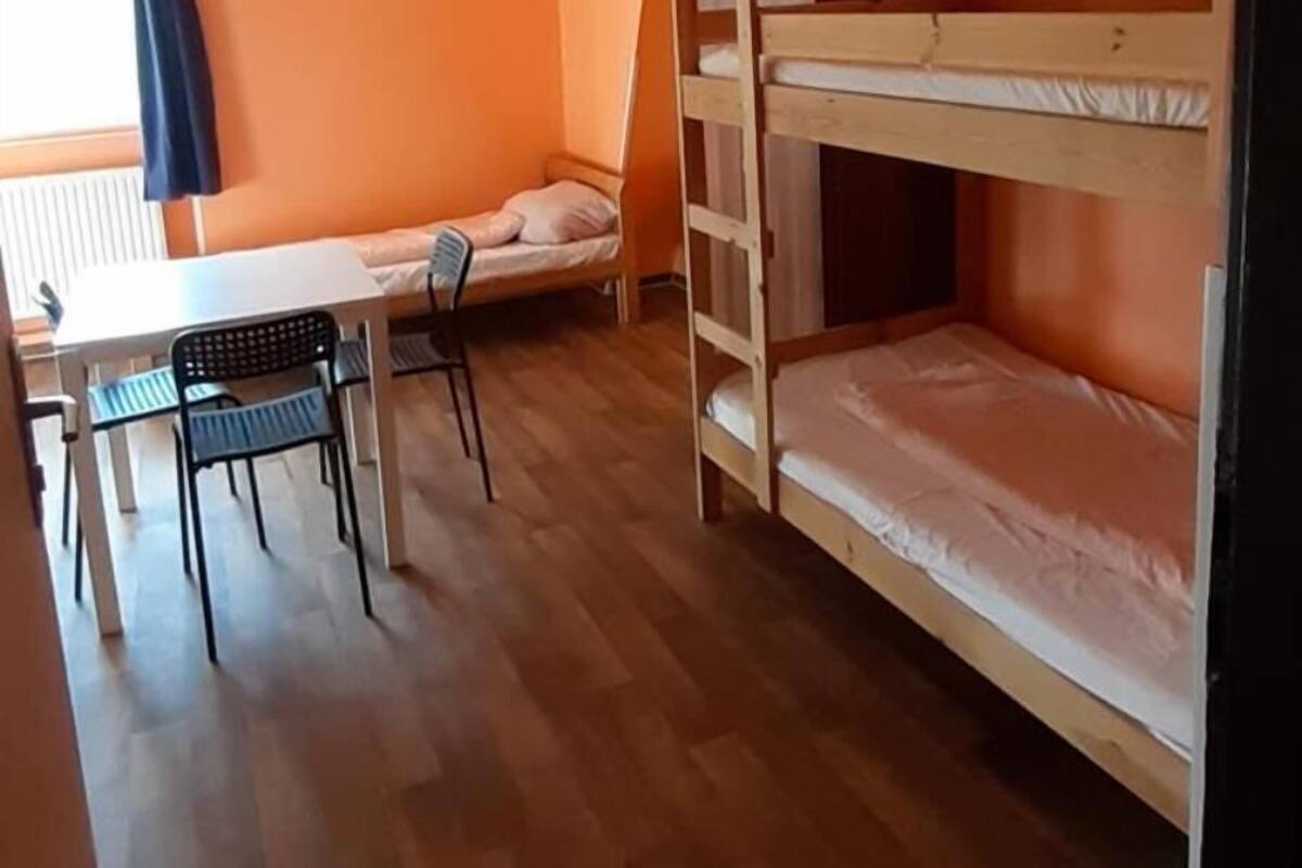 Une pièce avec un lit superposé, une table avec des chaises et une fenêtre avec des rideaux.