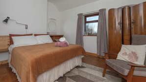 A bedroom with a bed, a chair, a wardrobe, a window with curtains, and a bedside table. - Amazing Country Stay In County Galway, Ireland (Oughterard)