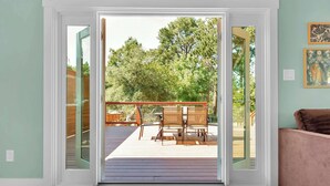 A room with a sliding glass door leading to an outdoor deck with a table and chairs. - Modern Country Home | Near Downtown & Bike Trail (Sebastopol)