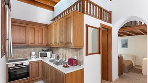 A compact kitchen with wooden cabinets, a microwave, a toaster, and a sink.