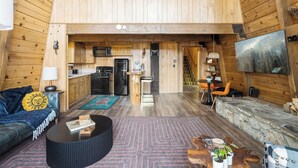 Interior de una cabaña de madera con cocina, comedor y zona de estar.
