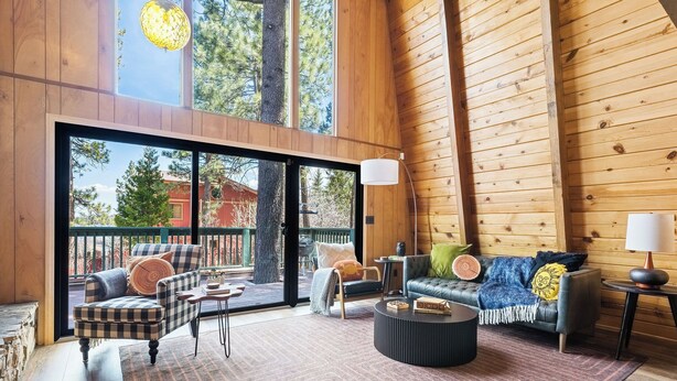 Amplia sala de estar con un gran ventanal corredero que da a una terraza exterior, amueblada con un sofá, sillones y una mesa de centro.