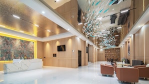 Eine moderne Hotelhalle mit einer Marmor-Rezeption, einer Sitzecke und einem großen, abstrakten Wandbild.