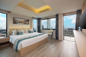 A modern hotel room with a large bed, a desk with a telephone, a chair, and a TV. - Xinmylin Boutique Resort Hotel (Pattaya)