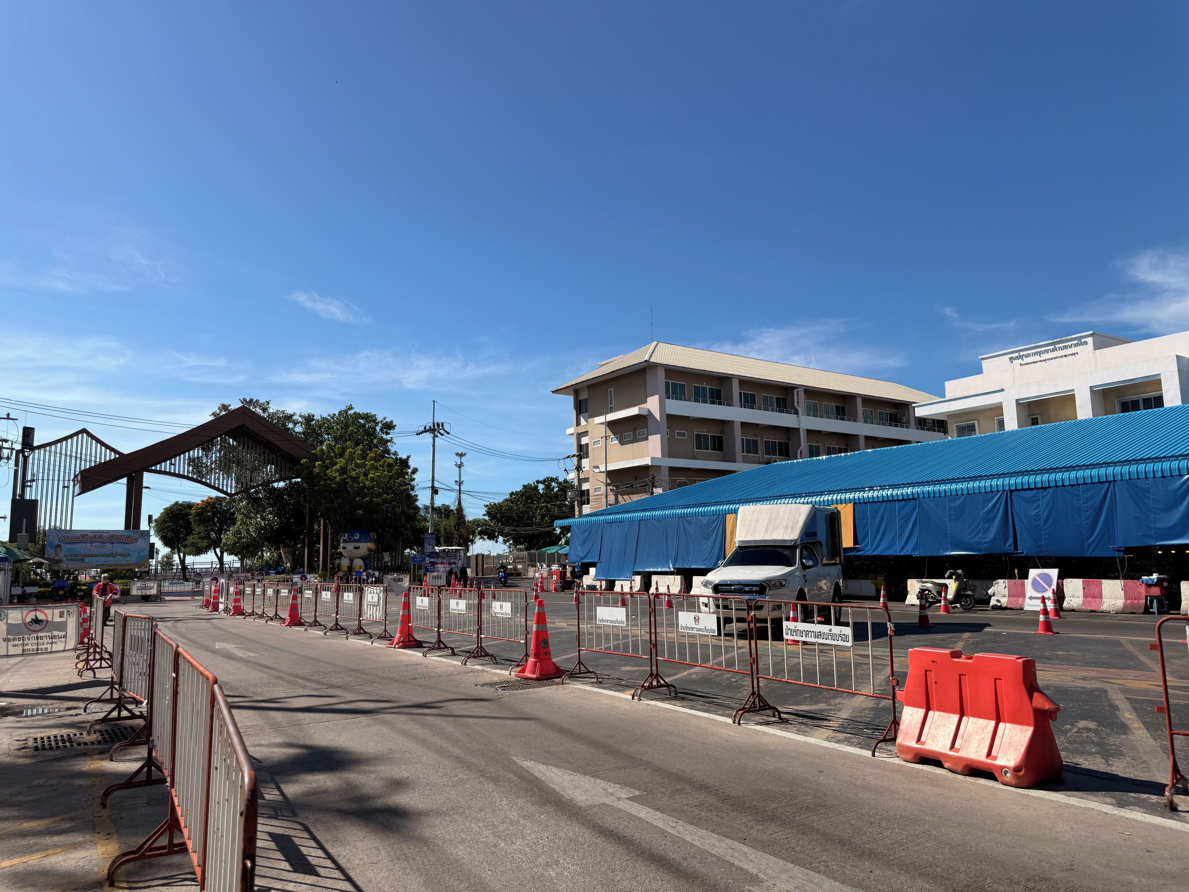 Una calle con barreras de tráfico y un edificio con toldo azul.