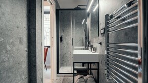 A modern bathroom with a glass-enclosed shower, a white sink, and a towel rack. - The Rubens Spagna (Rome)