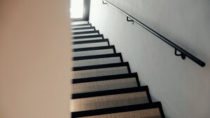A staircase with a handrail and a textured floor. - The Rubens Spagna (Rome)