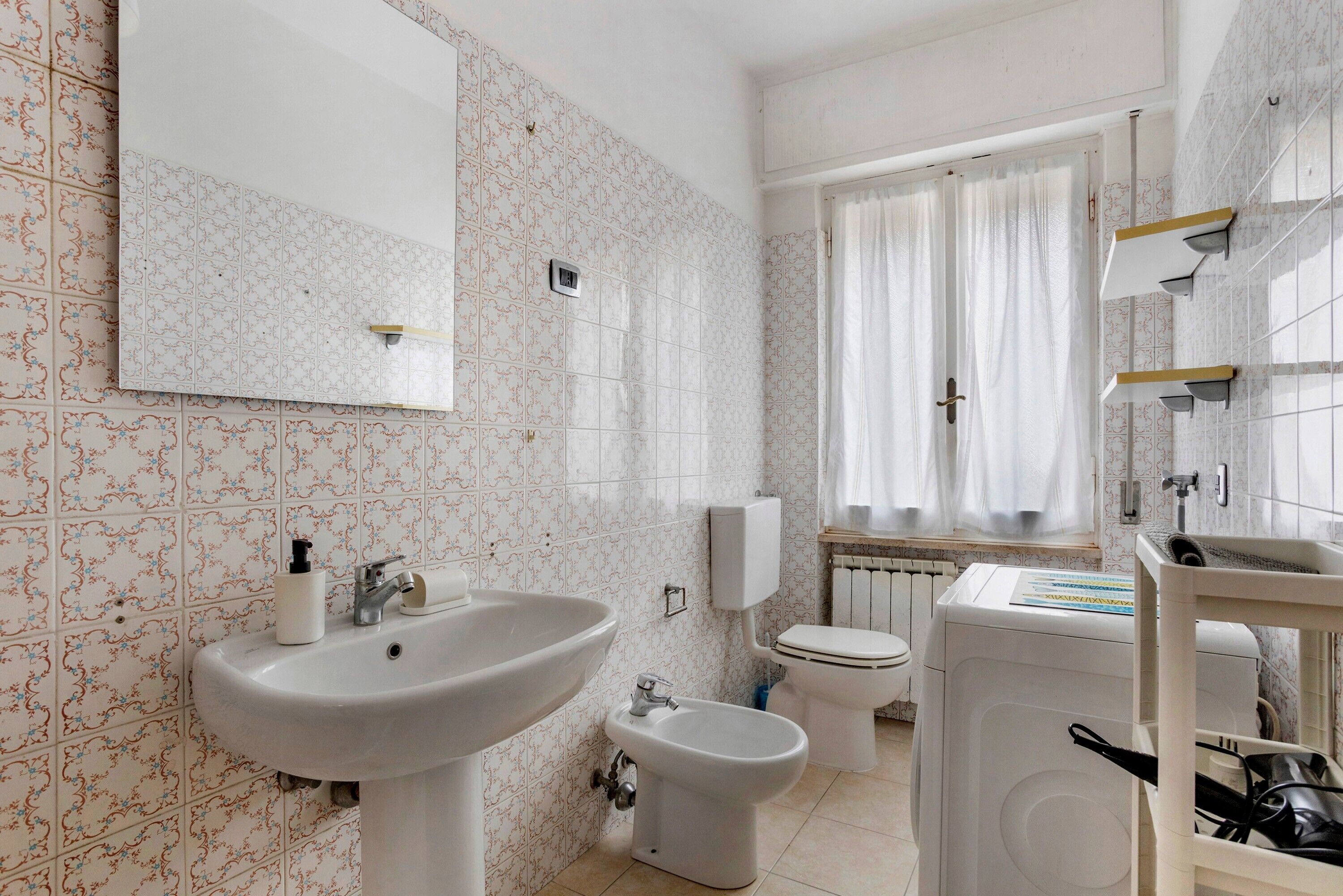 A bathroom with a sink, bidet, toilet, and a washing machine.