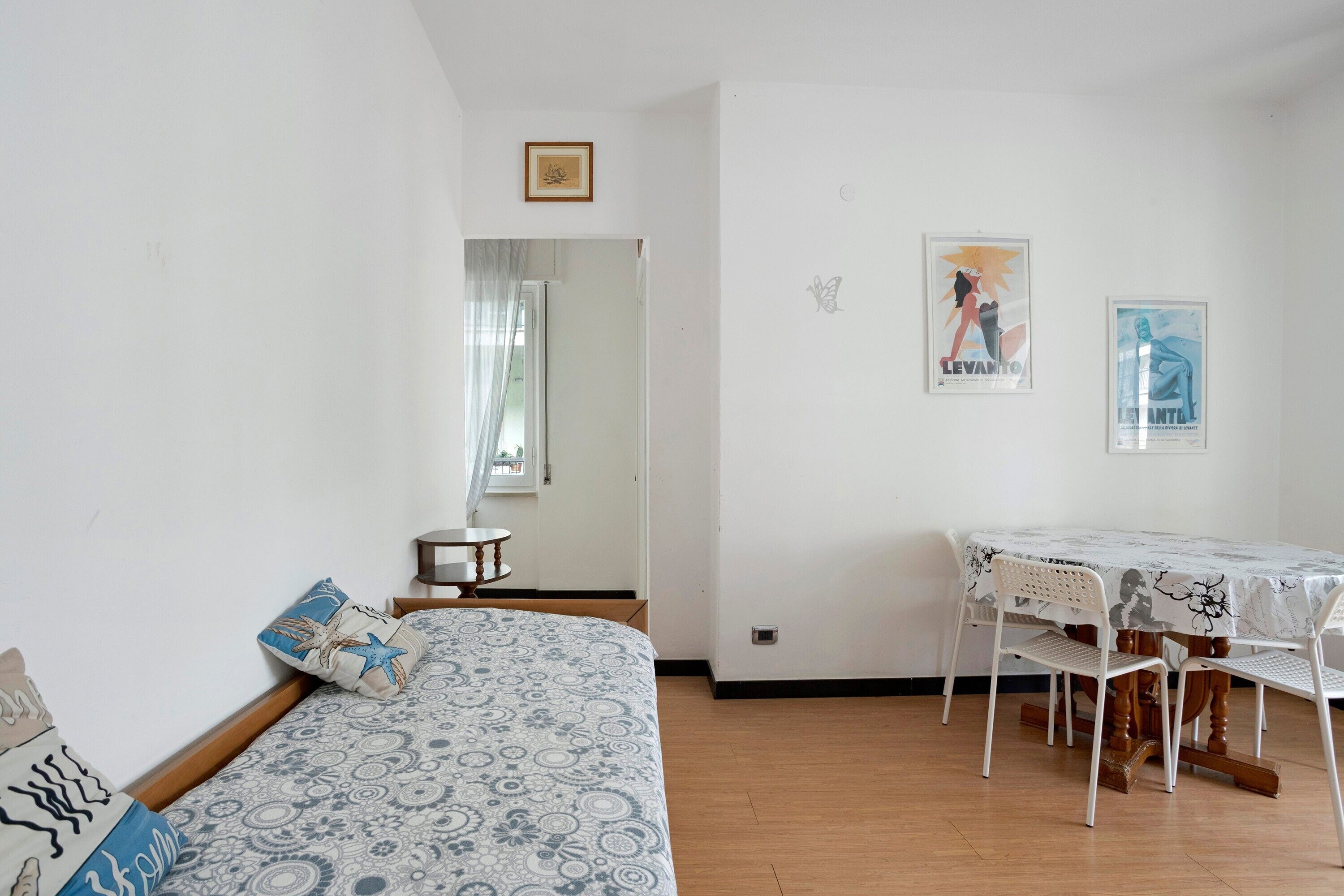 A room with a bed, a dining table with chairs, a small table, and a mirror.