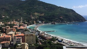 Un pueblo costero con edificios, una playa y montañas al fondo.