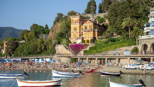 Una zona costera con barcos, una playa y un edificio con balcón con vistas al agua.