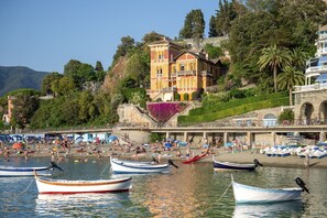 Una zona costera con barcos, una playa y un edificio con balcón con vistas al agua.
