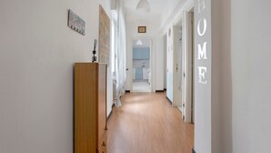 Un pasillo con piso de madera, un radiador, un perchero y una puerta con la leyenda 'HOME'.